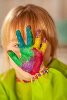 Salgın sırasında evde suluboya boyasının arkasına saklanan küçük bir kız.