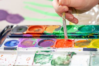 Salgın sırasında evde suluboya kullanan küçük bir kız.