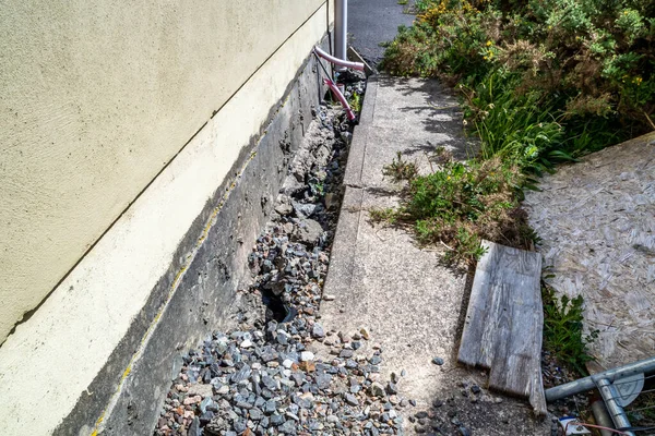 Разбитые трубы и пешеходная дорожка из-за оседания здания на торфянике — стоковое фото