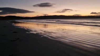 Donegal, İrlanda 'daki Portnoo Narin plajında gün batımında kumsala yağmur yağıyor..