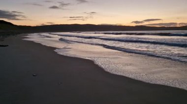 Donegal, İrlanda 'daki Portnoo Narin plajında gün batımında kumsala yağmur yağıyor..
