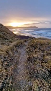 Donegal, İrlanda 'daki Portnoo Narin plajında gün batımında kumsala yağmur yağıyor..