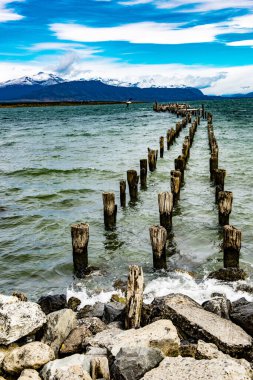 Puerto Natales, Şili 'deki Ultima Esperanza Boğazı' ndaki eski kırık iskele ve dağlar.. 