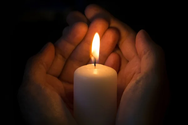 Человеческие руки держат горящую свечу — стоковое фото