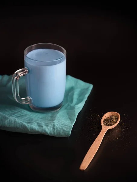 Moon milk is a drink made from milk and blue water. Thai flower tea in a glass Cup on a black background