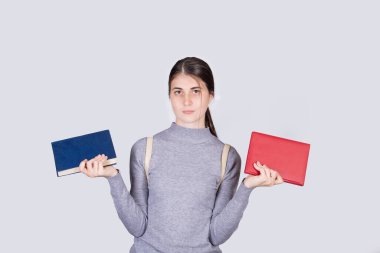 Şaşırmış genç kız öğrenci ne okuyacağını düşünerek el ele tutuşuyor. Seçim ikilemi, kırmızı maviye karşı. Eğitim ve edebiyat konsepti. Şüpheli okuyucu seçmek zorunda..