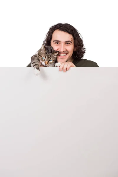 快乐的年轻人拥抱着他可爱的宠物猫 站在一面空白的横幅后面做广告和发短信 空白页 文本公告的复制空间 无忧无虑快乐的男性 营销简洁 — 图库照片