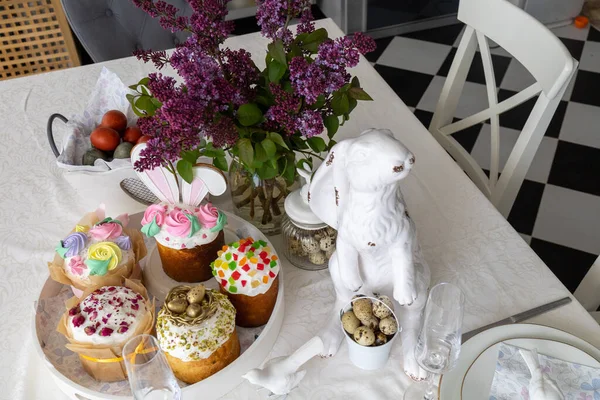 Easter. Easter cakes, lilac, hare, painted eggs, holiday, dining table with white tablecloth