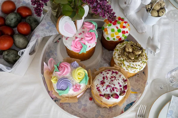 Ostern. Osterkuchen, Flieder, Hase, bemalte Eier, Urlaub, Esstisch mit weißer Tischdecke Stockbild