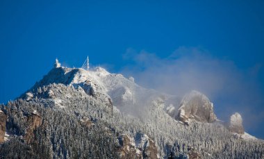 Kışın dağ zirvesi ve açık mavi gökyüzü. Ceahlau, Romanya