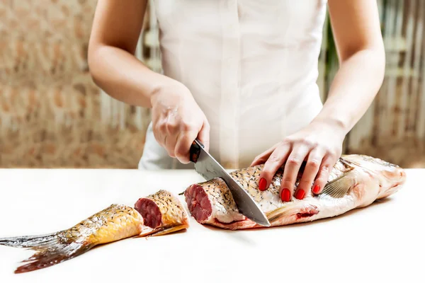 Flicka med en kniv skär fisken — Stockfoto