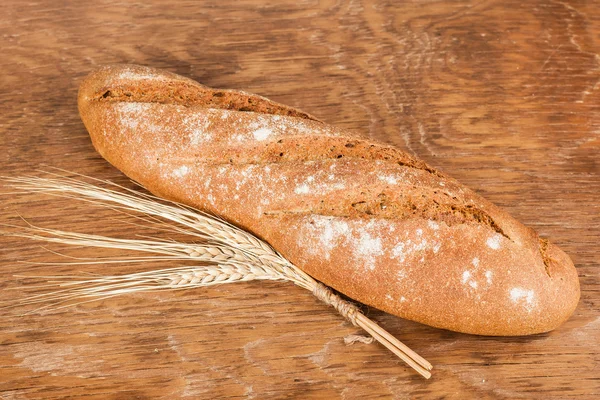 Pan negro con espigas de trigo — Foto de Stock