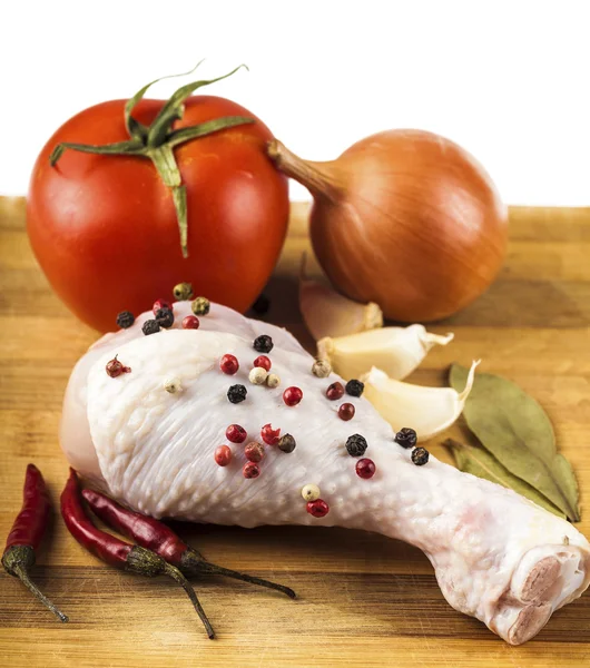 Raw chicken leg on a wooden board with spices and vegetables — Stock Photo, Image