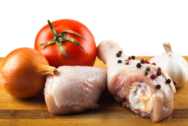 Marinated chicken legs on a wooden board with spices and vegetables — Stock Photo, Image