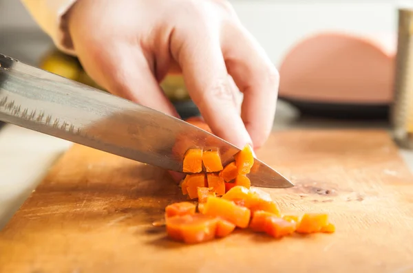 Cozinheiro corta uma faca ferveu a cenoura — Fotografia de Stock