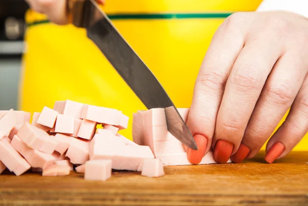 Женщина режет кубики колбасы — стоковое фото