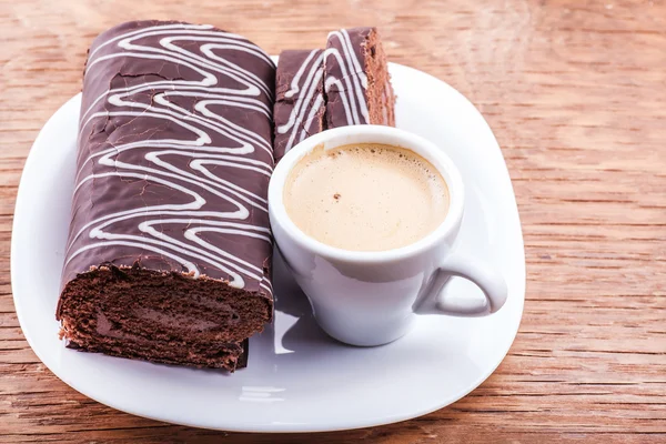 Rolo de chocolate com uma xícara de café — Fotografia de Stock