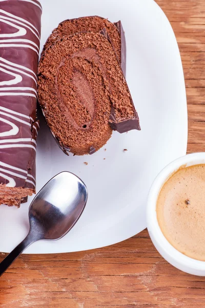 Chocolate roll with a cup of coffee close-up — Stock Photo, Image