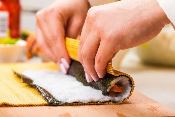Hands turns nori sheet with filling — Stock Photo, Image