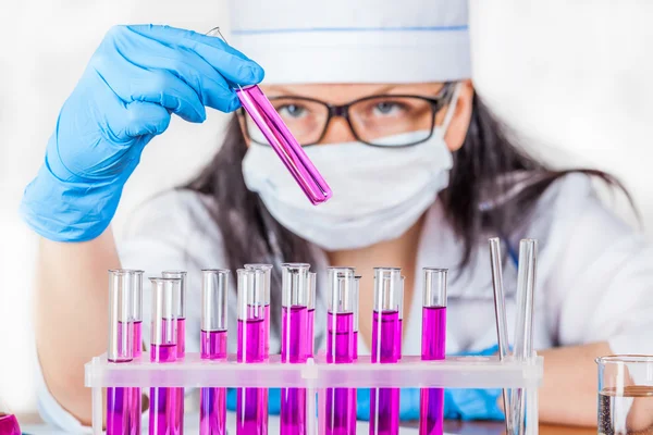 Laboratorian inspects the contents of the test tubes closeup — Stock Photo, Image