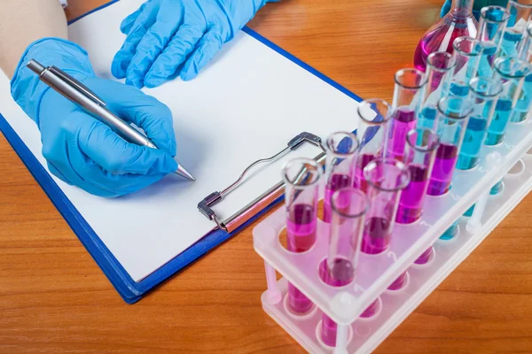 Laboratorian describes the result with test tubes — Stock Photo, Image