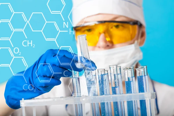 Woman chemist examines test tube — Stock Photo, Image