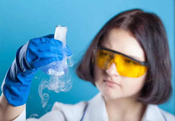 Woman chemist examines test tube — Stock Photo, Image
