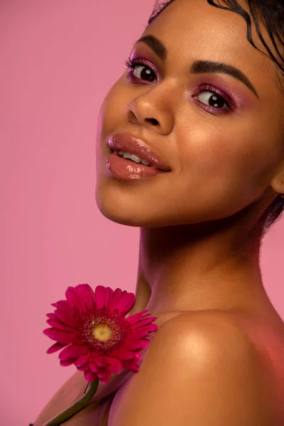 Porträtt av en vacker ung afroamerikansk kvinna med blomma. Vår- eller sommarkoncept. Stockbild