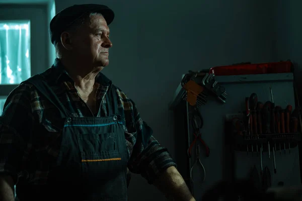 Anciano con un martillo trabaja en un taller Imagen de stock