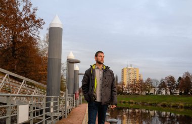Half portrait of young caucasian man in jacket walking on shipyard on Vltava river. Ceske Budejovice, Czech republic