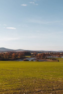 Czech autumn landscape. Dry pond Dehtar with meadow, trees and distant hill at day time, toned photo