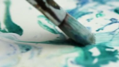 Yeşil ve beyaz boyayı karıştıran fırça görüntülerini kapat