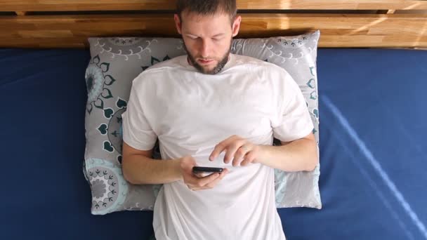 Młody Dorosły Mężczyzna Pomocą Smartfona Łóżku Widok Nad Głową — Wideo stockowe
