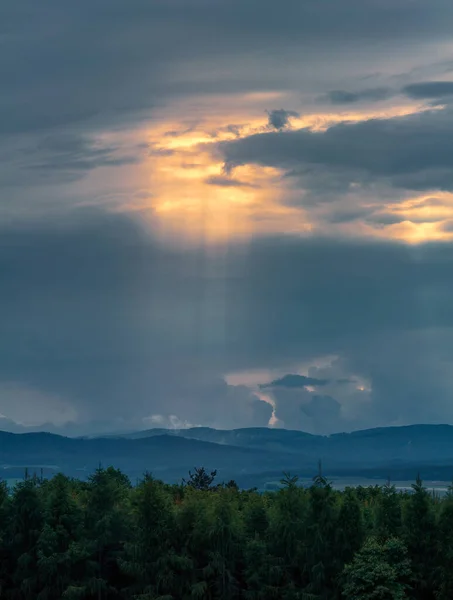 Dramatic sky with god light over forest and distant hill. Czech landscape