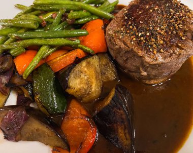 Izgara sebzeli sığır filetosu ve beyaz tabakta barbekü sosu.