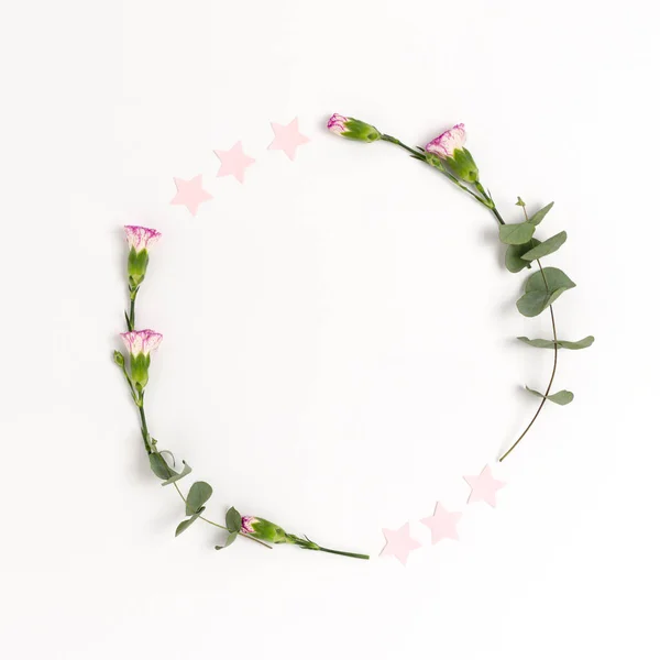 Wreath made of confetti, flowers and eucalyptus on a white background.