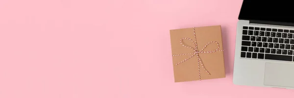 Header with laptop and gift box on a pink background. Online shopping minimalist composition with place for text.