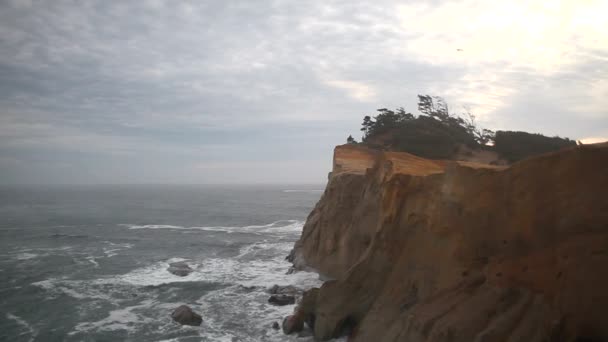 Schwenkfilm von krachenden Wellen mit bewölktem Himmel und Sandstrand am Kap Kiwanda entlang des Pazifischen Ozeans in der Pazifischen Stadt oregon 1080p — Stockvideo