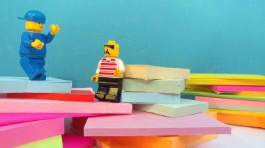 Duvarın yanında elinde post-it olan iki lego adam.