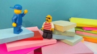 Duvarın yanında elinde post-it olan iki lego adam.