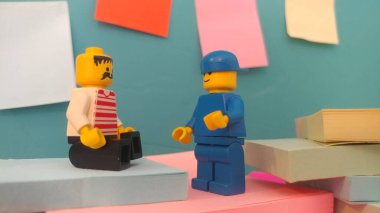Duvarın yanında elinde post-it olan iki lego adam.