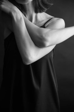 Siyah arka planda güzel bir kızın siyah beyaz portresi, kadın vücudunun minimalizmi ve güzelliği.