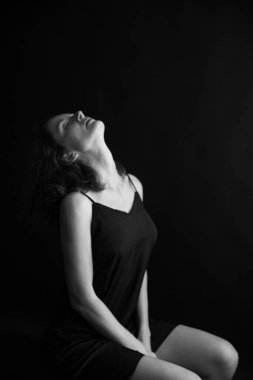 Siyah arka planda güzel bir kızın siyah beyaz portresi, kadın vücudunun minimalizmi ve güzelliği.