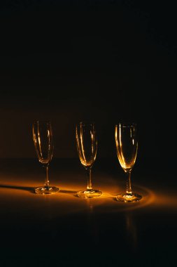 Birkaç şampanya kadehinden oluşan bir grup, koyu bir arka plan karşısında güzelce aydınlatılıyor. Şenlikli bir kompozisyon. Metin için boşluk