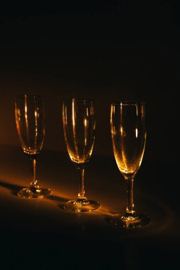Birkaç şampanya kadehinden oluşan bir grup, koyu bir arka plan karşısında güzelce aydınlatılıyor. Şenlikli bir kompozisyon. Metin için boşluk