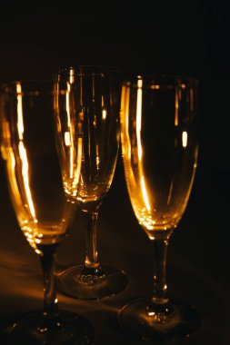 Birkaç şampanya kadehinden oluşan bir grup, koyu bir arka plan karşısında güzelce aydınlatılıyor. Şenlikli bir kompozisyon. Metin için boşluk