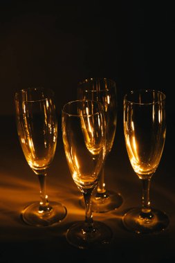 Birkaç şampanya kadehinden oluşan bir grup, koyu bir arka plan karşısında güzelce aydınlatılıyor. Şenlikli bir kompozisyon. Metin için boşluk