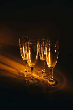Birkaç şampanya kadehinden oluşan bir grup, koyu bir arka plan karşısında güzelce aydınlatılıyor. Şenlikli bir kompozisyon. Metin için boşluk
