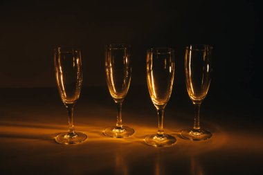 Birkaç şampanya kadehinden oluşan bir grup, koyu bir arka plan karşısında güzelce aydınlatılıyor. Şenlikli bir kompozisyon. Metin için boşluk