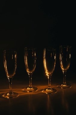 Birkaç şampanya kadehinden oluşan bir grup, koyu bir arka plan karşısında güzelce aydınlatılıyor. Şenlikli bir kompozisyon. Metin için boşluk